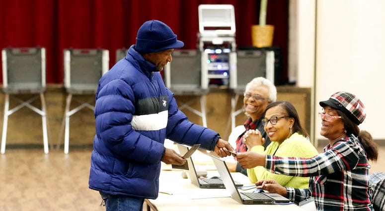 L.M. Walker shows his identification to vote in a runoff election Tuesday, Nov. 27, 2018 in Gulfport, Miss.