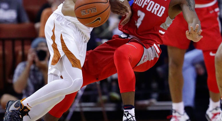 Texas guard Elijah Mitrou-Long, left, is fouled by Radford guard Cle'von Greene (3) as he drives with the ball during the first half of an NCAA college basketball game Friday, Nov. 30, 2018, in Austin, Texas. (