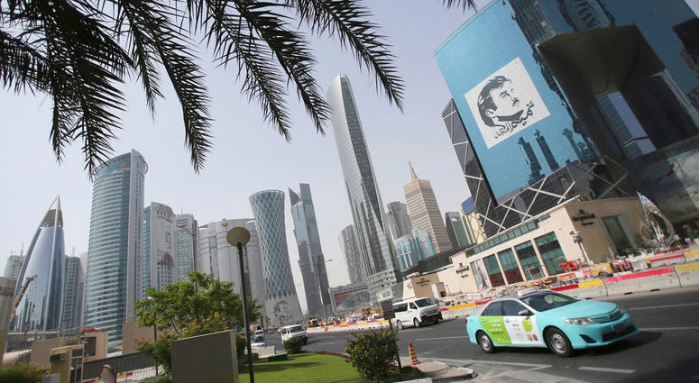 In this May 5, 2018, file photo, a taxi passes by a building with an image of emir of Qatar, Sheikh Tamim bin Hamad Al Thani, in Doha, Qatar. (AP Photo/Kamran Jebreili, File)