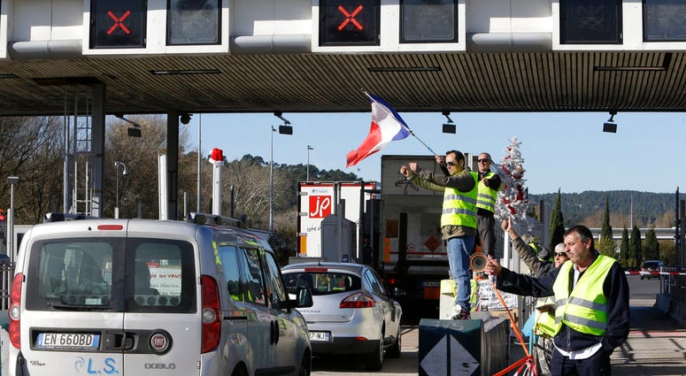 Demonstrators wearing yellow vests open the toll gates on a motorway near Aix-en-Provence, southeastern France, Tuesday, Dec. 4, 2018.