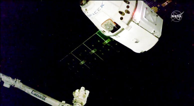 In this image taken from NASA Television, the SpaceX Dragon cargo spacecraft approaches the robotic arm for docking to the International Space Station, Saturday, Dec. 8, 2018.