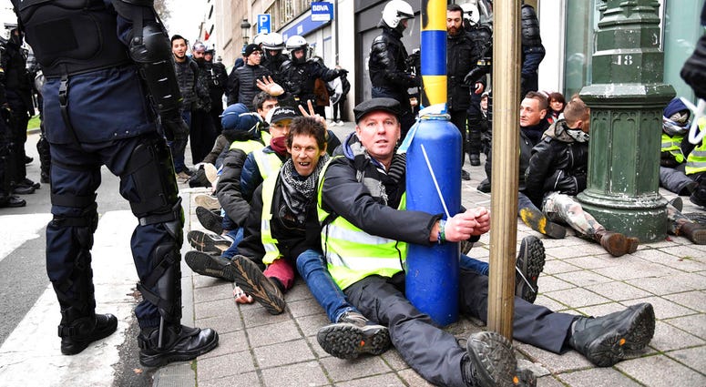 A police stands by as protestors are detained during a demonstration in Brussels, Saturday, Dec. 8, 2018.