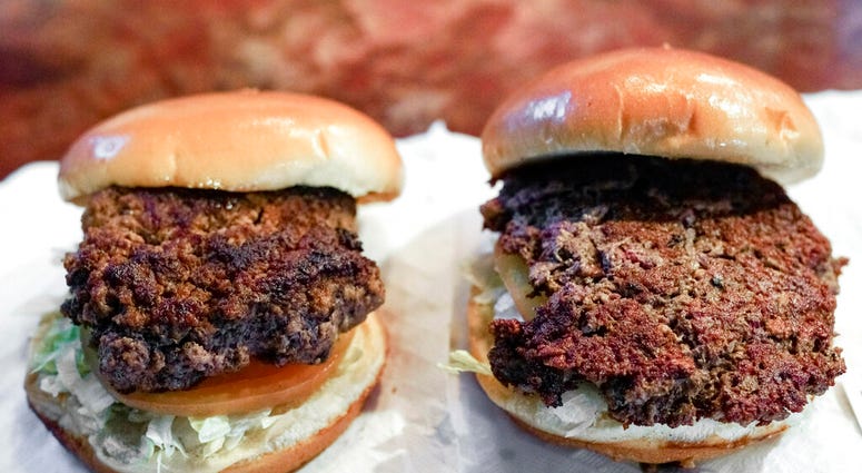 A conventional beef burger, left, is seen Friday, Jan. 11, 2019, next to "The Impossible Burger", right, a plant-based burger containing wheat protein, coconut oil and potato protein among it's ingredients.
