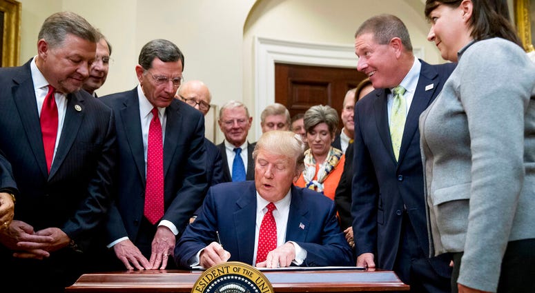 Tuesday, Feb. 28, 2017, file photo, President Donald Trump signs the Waters of the United States (WOTUS) executive order, in the Roosevelt Room in the White House in Washington, which directs the Environmental Protection Agency to withdraw the WOTUS rule
