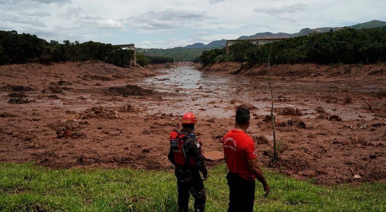 Firefights survey mud at site of dam collapse