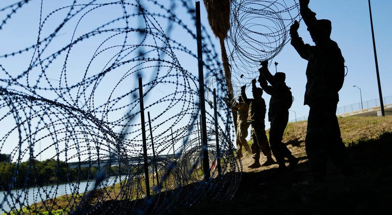 In this Friday, Nov. 16, 2018, file photo, members of the U.S. military install multiple tiers of concertina wire along the banks of the Rio Grande near the Juarez-Lincoln Bridge at the U.S.-Mexico border,