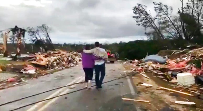 Couple walking through debris in Lee County, Alabama