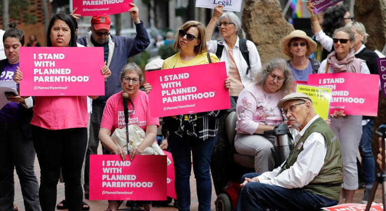 In this July 10, 2018 file photo, protesters hold signs supporting Planned Parenthood in Seattle, as they demonstrate against President Donald Trump. (AP Photo/Ted S. Warren, File)