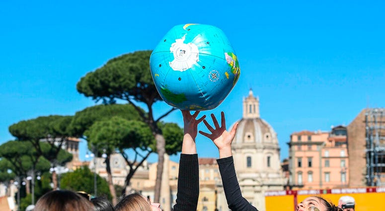 Students play with an inflatable globe as they march to demand action on climate change, in Rome, Friday, March 15, 2019. (Alessandro Di Meo/ANSA via AP)