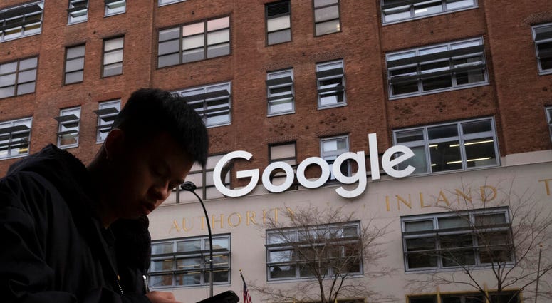 In this Dec. 17, 2018, file photo, a man using a mobile phone walks past Google offices in New York. (AP Photo/Mark Lennihan, File)
