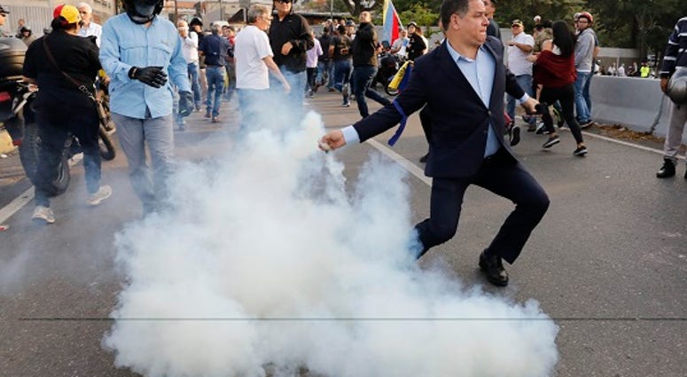 An opponent to Venezuela's President Nicolas Maduro returns a tear gas canister in Caracas, Venezuela, Monday, April 29, 2019. (AP Photo/Ariana Cubillos)