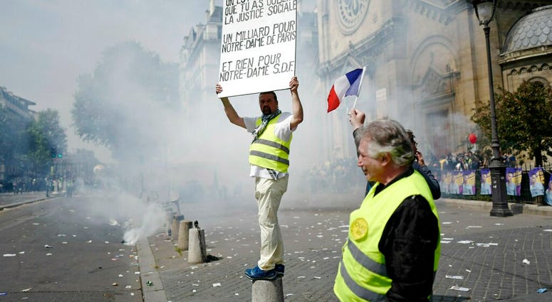 A protestor holds a banner criticising the funding of the Notre Dame cathedral renovations, during a May Day demonstration in Paris, Wednesday, May 1, 2019. (AP Photo/Kamil Zihnioglu)