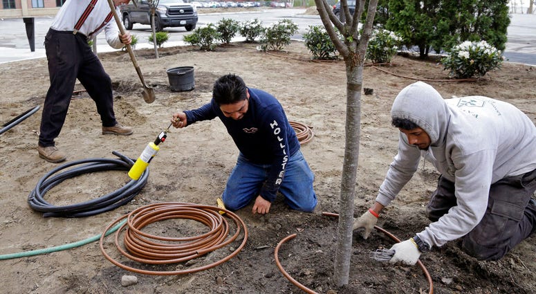 Stephen Faulkner, far left, owner of Faulkner's Landscaping & Nursery, installs an irrigation system alongside workers Gonsalo Garcia, center, and Jalen Murchison, right, at a landscape project in Manchester, N.H. (AP Photo/Elise Amendola) Stephen Faulkner, far left, owner of Faulkner's Landscaping & Nursery, installs an irrigation system alongside workers Gonsalo Garcia, center, and Jalen Murchison, right, at a landscape project in Manchester, N.H. (AP Photo/Elise Amendola)