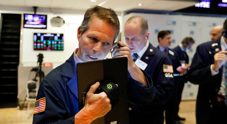 In this May 1, 2019, file photo, trader Robert Charmak, left, works on the floor of the New York Stock Exchange. (AP Photo/Richard Drew, File)