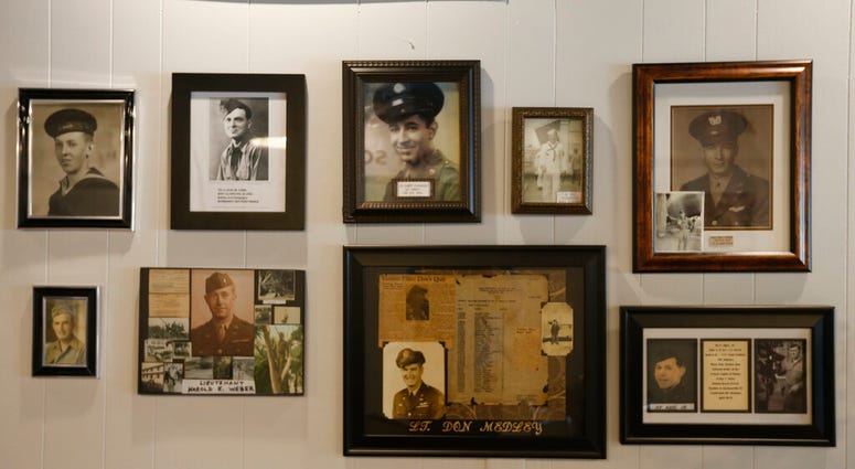 n this May 6, 2019, photo, a group of photos are on display at a tribute center for the Bedford Boys in Bedford, Va. The 75th anniversary of the D-Day invasion of Normandy has a solemn significance for Bedford, who lost 20 local men. (AP Photo/Steve Helbe