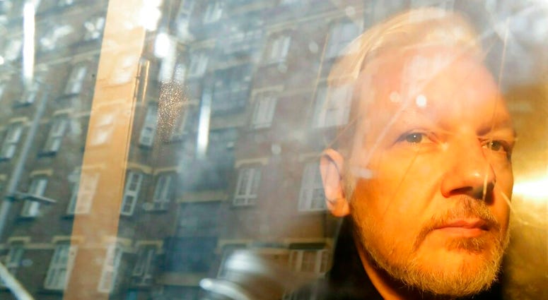 FILE - In this Wednesday May 1, 2019 file photo, buildings are reflected in the window as WikiLeaks founder Julian Assange is taken from court, where he appeared on charges of jumping British bail seven years ago, in London. Swedish prosecutors plan to de