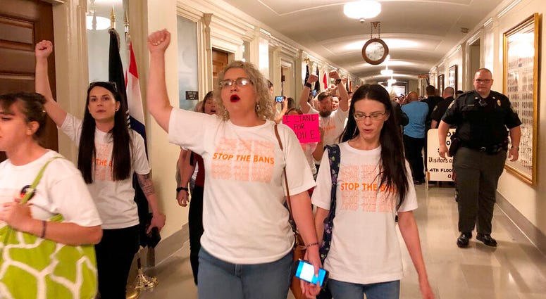 Protesters march through the halls of the Missouri Capitol outside the House chamber on Friday, May 17, 2019, in Jefferson City, Missouri, in opposition to legislation prohibiting abortions at eight weeks of pregnancy. (AP Photo/David A. Lieb)