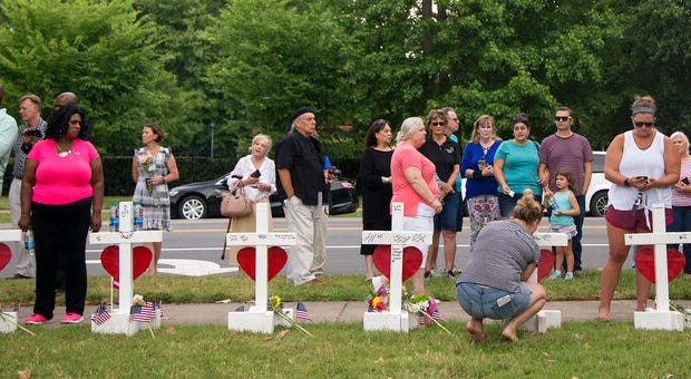 Community members stand by the 12 crosses at the memorial located by Building 11 of the Virginia Beach Municipal Center, Sunday, June 2, 2019, in Virginia Beach. (Sarah Holm/The Virginian-Pilot via AP)