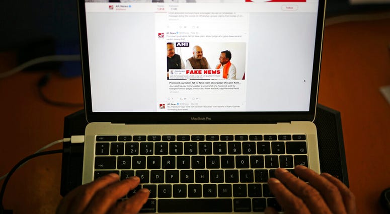 In this Tuesday, April 2, 2019, file photo, a man browses through the Twitter account of Alt News, a fact-checking website. (AP Photo/Altaf Qadri, File)