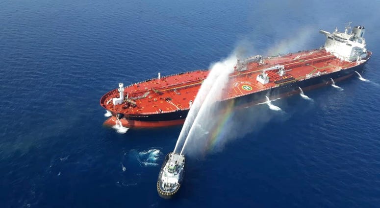 An Iranian navy boat sprays water to extinguish a fire on an oil tanker in the sea of Oman, Thursday, June 13, 2019. (AP Photo/Tasnim News Agency)