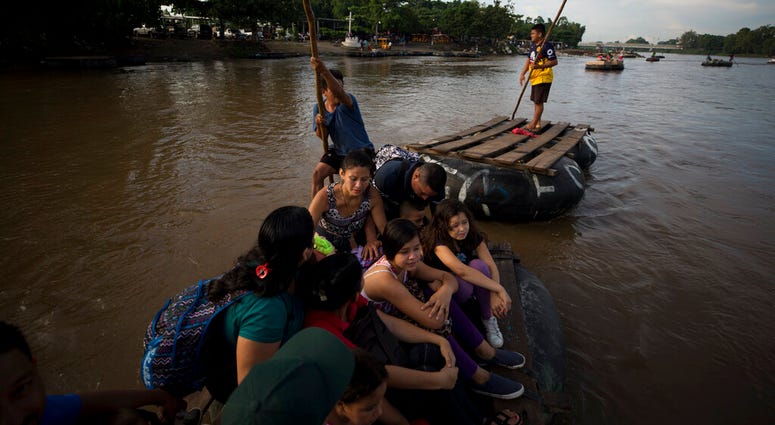 A group of more than a dozen Honduran migrants ride a raft across the Suchiate River after between Tecun Uman, Guatemala, left, and Ciudad Hidalgo, Mexico, Friday, June 14, 2019. Raftsmen and riverfront business operators said the flow of migrants through