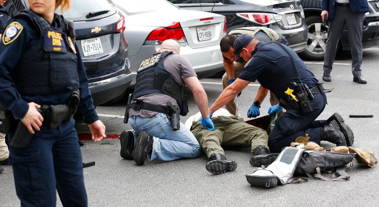 Law enforcement officers attend to an injured shooter in a parking lot after he fired shots at the Earle Cabell Federal Building in downtown Dallas, Monday, June 17, 2019. (Tom Fox/The Dallas Morning News)