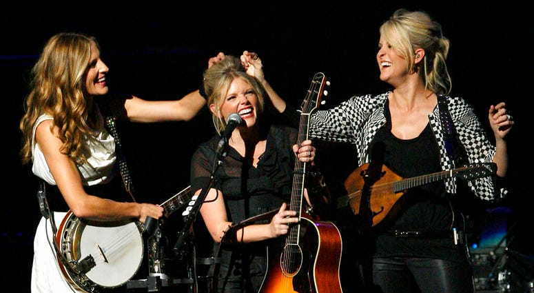 FILE - In this Oct. 18, 2007 file photo, Emily Robison, left, and Martie Maguire, right, adjust Natalie Maines' hair as the Dixie Chicks perform at the new Nokia Theatre in Los Angeles. (AP Photo/Gus Ruelas, file) FILE - In this Oct. 18, 2007 file photo, Emily Robison, left, and Martie Maguire, right, adjust Natalie Maines' hair as the Dixie Chicks perform at the new Nokia Theatre in Los Angeles. (AP Photo/Gus Ruelas, file)