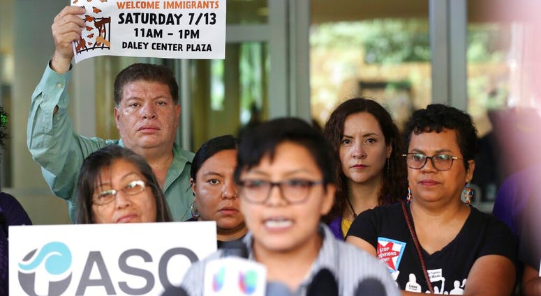 Demonstrators hold placards as Rey Wences, organizer at Organized Communities Against Deportations (OCAD) addresses reporters outside the U.S. Citizenship and Immigration Services offices in Chicago, Thursday, July 11, 2019. (AP Photo/Amr Alfiky)