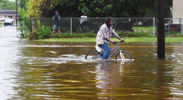 A man tries to bike through the flooding from the rains of storm Barry on LA Hwy 675 in New Iberia, La., Sunday, July 14, 2019. (Henrietta Wildsmith/The Shreveport Times via AP)