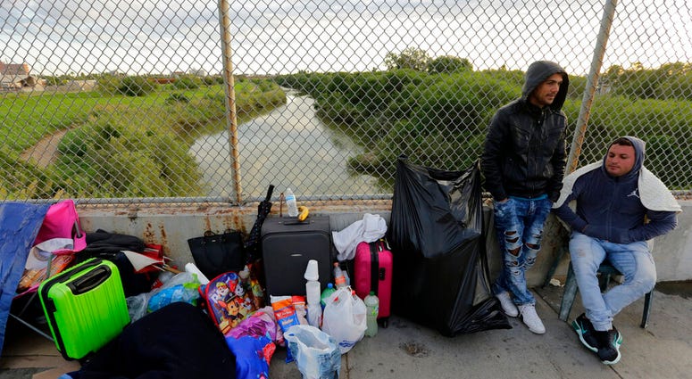FILE - In this Nov. 2, 2018, file photo, Yenly Morales,left, and Yenly Herrera, right, immigrants from Cuba seeking asylum in the United States, wait on the Brownsville and Matamoros International Bridge in Matamoros, Mexico. The U.S. government will expa