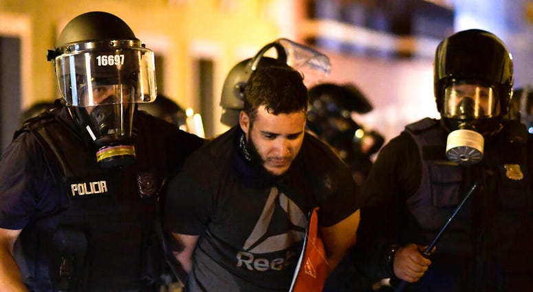 Police arrest a demonstrator during clashes demand the resignation of Gov. Ricardo Rossello in San Juan, Puerto Rico, Monday, July 22, 2019. Protesters are demanding Gov. Ricardo Rossello step down following the leak of an offensive, obscenity-laden onlin