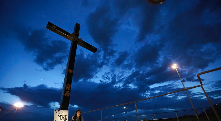 A woman sits next to a sign with a message that reads: ¨No More Guns! Make Love¨, in Juarez, Mexico, Saturday, Aug. 3, 2019, where people are gathering for a vigil for the 3 Mexican nationals who were killed in an El Paso shopping-complex shooting. Twenty