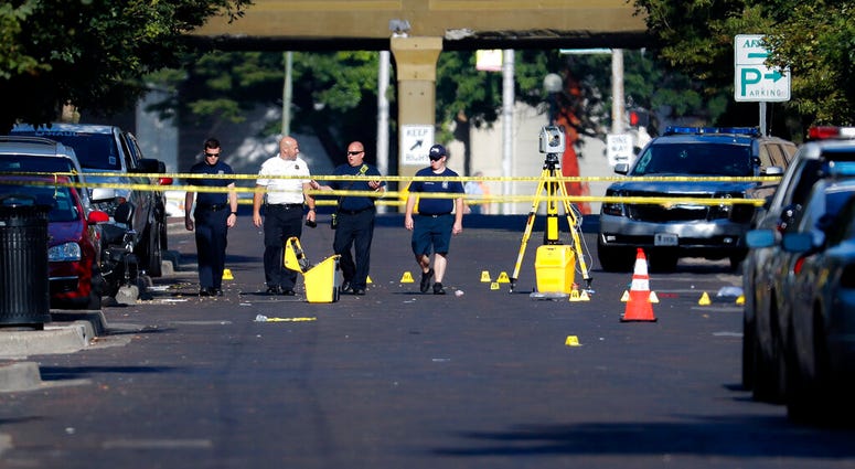 Authorities walk among evidence markers at the scene of a mass shooting, Sunday, Aug. 4, 2019, in Dayton, Ohio. (AP Photo/John Minchillo)