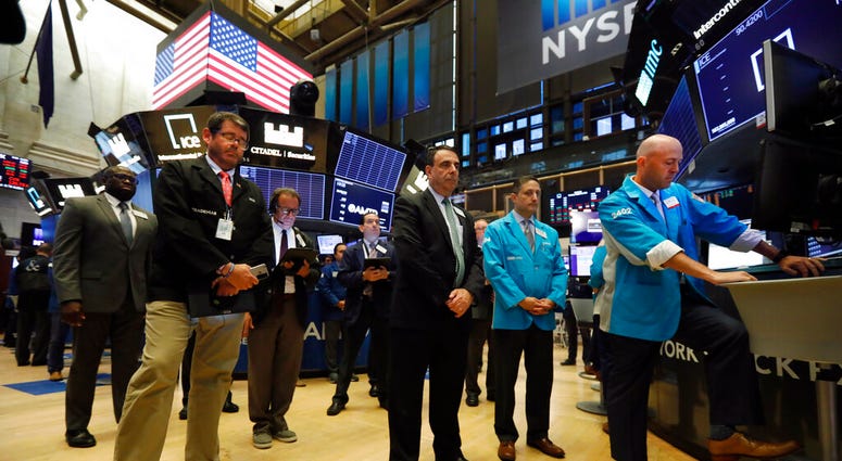 Traders pause for a moment of silence on the floor of the New York Stock Exchange, for the victims of the weekend shootings, Monday, Aug. 5, 2019. (AP Photo/Richard Drew)