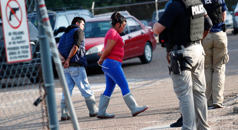 Two people are taken into custody at a Koch Foods Inc. plant in Morton, Miss., on Wednesday, Aug. 7, 2019. U.S. immigration officials raided several Mississippi food processing plants on Wednesday and signaled that the early-morning strikes were part of a