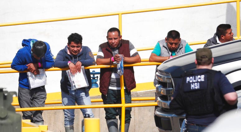 Handcuffed workers await transportation to a processing center following a raid by U.S. immigration officials at Koch Foods Inc., plant in Morton, Miss. (AP Photo/Rogelio V. Solis)