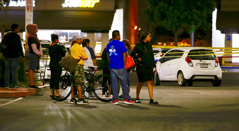 Members of a church group wait behind police lines, fearing they know one person killed by a man stabbing people at a Subway, in Santa Ana, Calif., Wednesday, Aug. 7, 2019. A man killed multiple people and wounded others in a string of robberies and stabb
