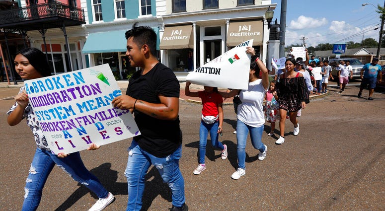 In this Aug. 11, 2019 photo, children of mainly Latino immigrant parents hold signs in support of them and those individuals picked up during an immigration raid at a food processing plant in Canton, Miss. (AP Photo/Rogelio V. Solis)