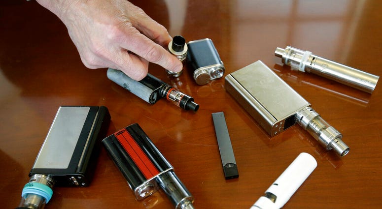 In this Tuesday, April 10, 2018 photo, Marshfield High School Principal Robert Keuther displays vaping devices that were confiscated from students in such places as restrooms or hallways at the school in Marshfield, Mass. I