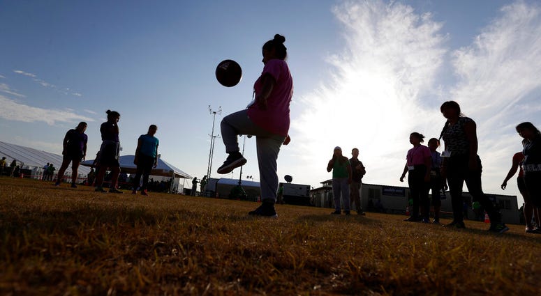 In this July 9, 2019, file photo, immigrants play soccer at the U.S. government's newest holding center for migrant children in Carrizo Springs, Texas. (AP Photo/Eric Gay, File)