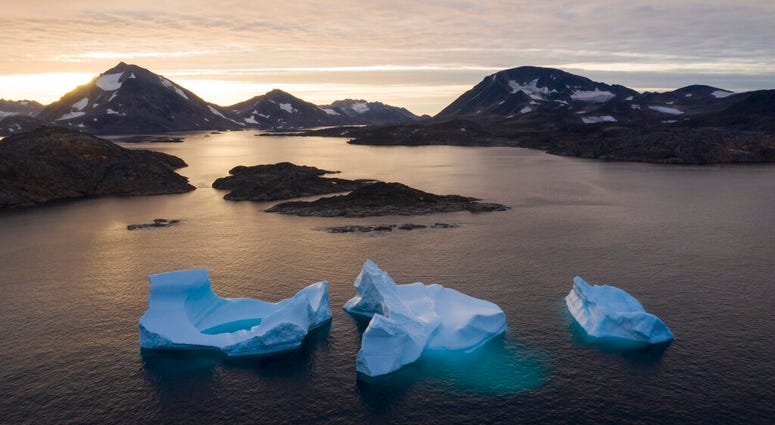 In this Aug. 15, 2019, photo, a boat navigates at night next to large icebergs in eastern Greenland. Greenland's ice has been melting for more than 20 years. (AP Photo/Felipe Dana)