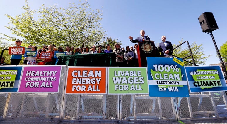 In this May 7, 2019, file photo, Washington Gov. Jay Inslee, second right, addresses the crowd before signing climate protection legislation in Seattle. (AP Photo/Elaine Thompson, File)