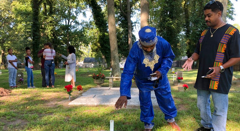 Andre Bradshaw, left, and Eric Jackson stand at an unmarked grave at the Tucker Family Cemetery in Hampton, Va. on Friday, Aug. 23, 2019. They are part of a larger family that traces its roots back to the first enslaved Africans to arrive in what is now V