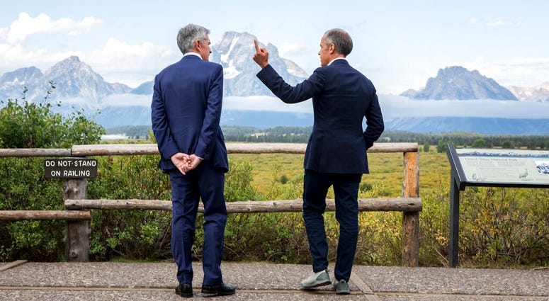 Federal Reserve Chairman Jerome Powell, left, and Bank of England Governor Mark Carney, right, pause in front of Mt. Moran after Powell's speech at the Jackson Hole Economic Policy Symposium on Friday, Aug. 23, 2019, in Jackson Hole, Wyo.