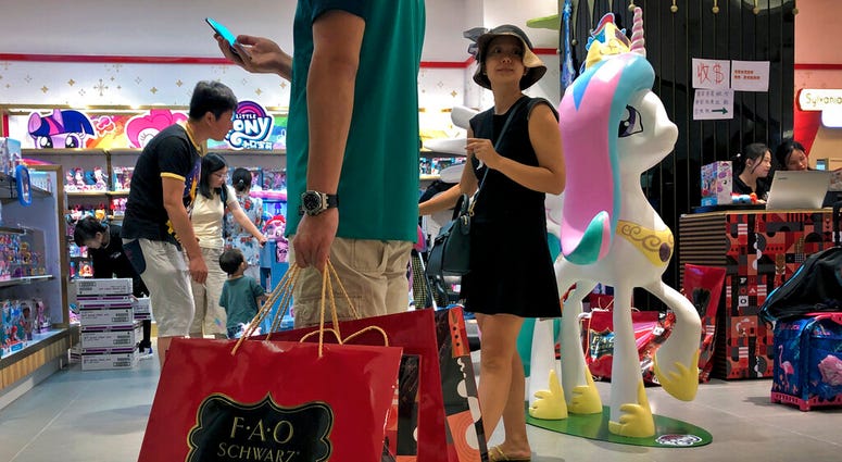 FILE - In this June 1, 2019, photo, file a man carries a paper bags containing toys purchased from the FAO Schwarz as people shop at the newly open FAO Schwarz toy store at the capital city's popular shopping mall in Beijing.