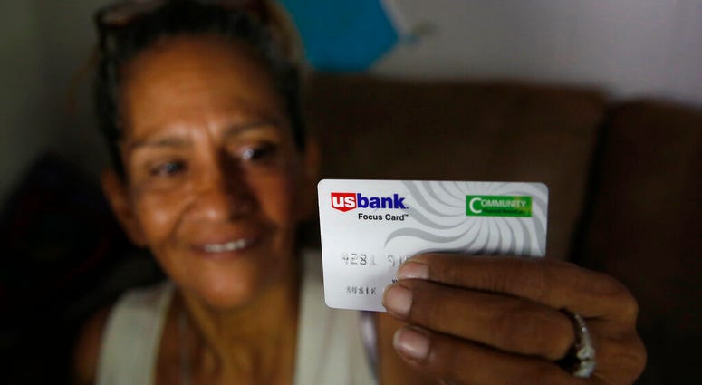 In this photo taken Wednesday, Aug. 14, 2019, Susie Garza displays the city provided debit card she receives monthly through a trial program in Stockton, Calif. Garza is participating in the Stockton Economic Empowerment Demonstration.
