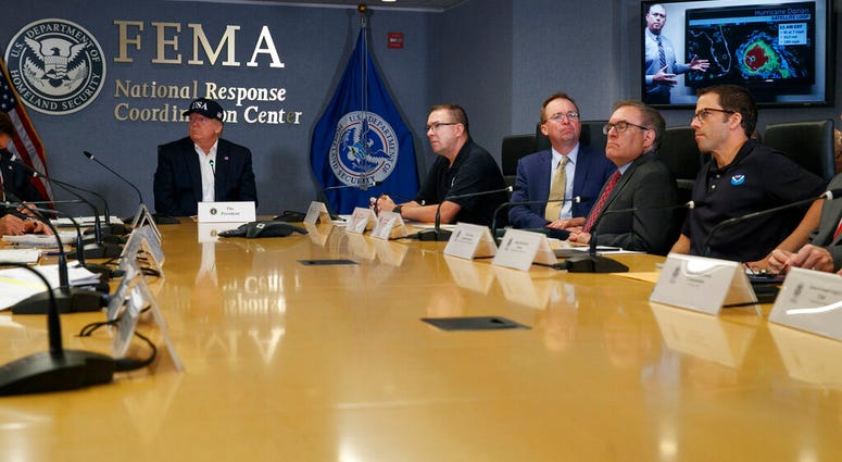 President Donald Trump, left, listens as Kenneth Graham, director of NOAA's National Hurricane Center, on screen, gives an update during a briefing about Hurricane Dorian at FEMA, Sunday, Sept. 1, 2019. (AP Photo/Jacquelyn Martin)