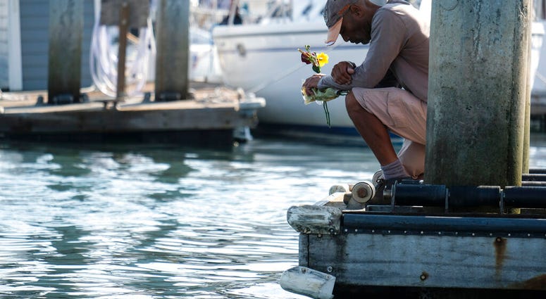 James Miranda, right, of Santa Barbara, holds flowers and takes a moment to reflect at a dock near the Sea Landing at Santa Barbara Harbor in Santa Barbara, Calif., Monday, Sept. 2, 2019.
