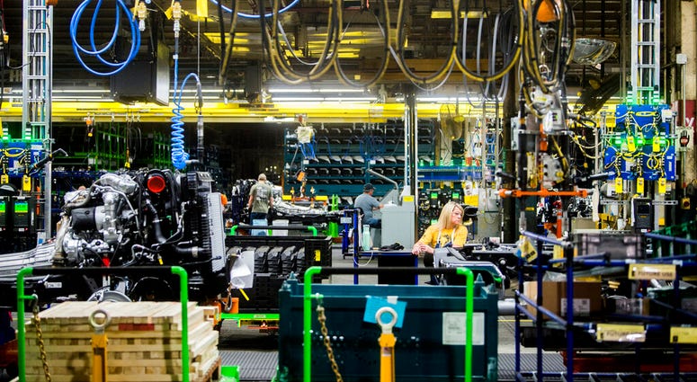 FILE - In this June 12, 2019, file photo General Motors employees work on the chassis line as they build the frame, power train and suspension onto the truck's body at the Flint Assembly Plant in Flint, Mich.