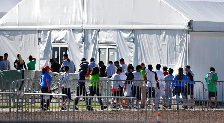 FILE- In this Feb. 19, 2019 file photo, children line up to enter a tent at the Homestead Temporary Shelter for Unaccompanied Children in Homestead, Fla.